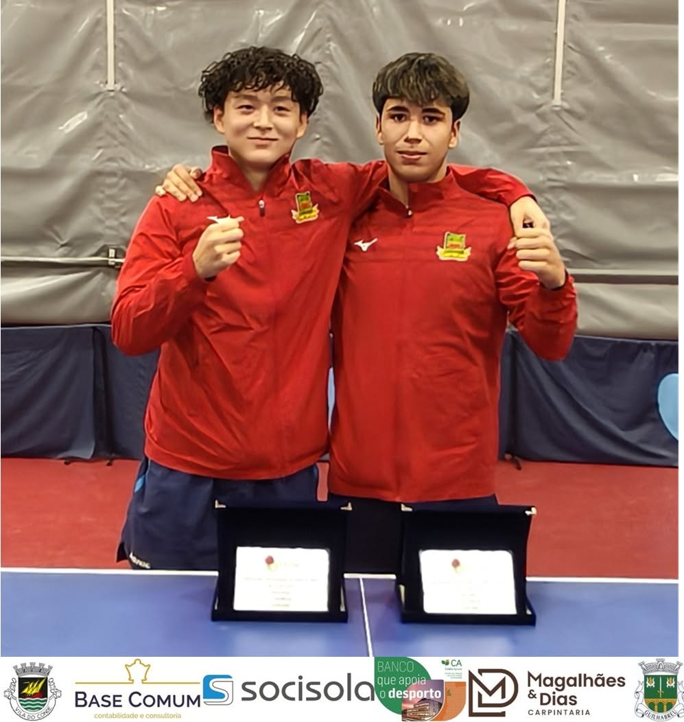 Dois atletas do clube, de camisola vermelha, posam juntos com os seus troféus; logótipos dos patrocinadores aparecem na faixa inferior.